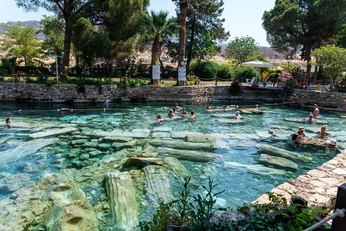 Badegäste im warmen Mineralwasser des Kleopatra-Antikpools in Pamukkale, am Grund liegen umgestürzte römische Säulen